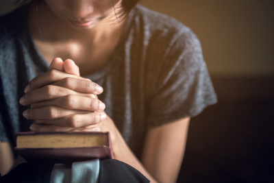 Soft focus on a hand of woman while praying for christian religion